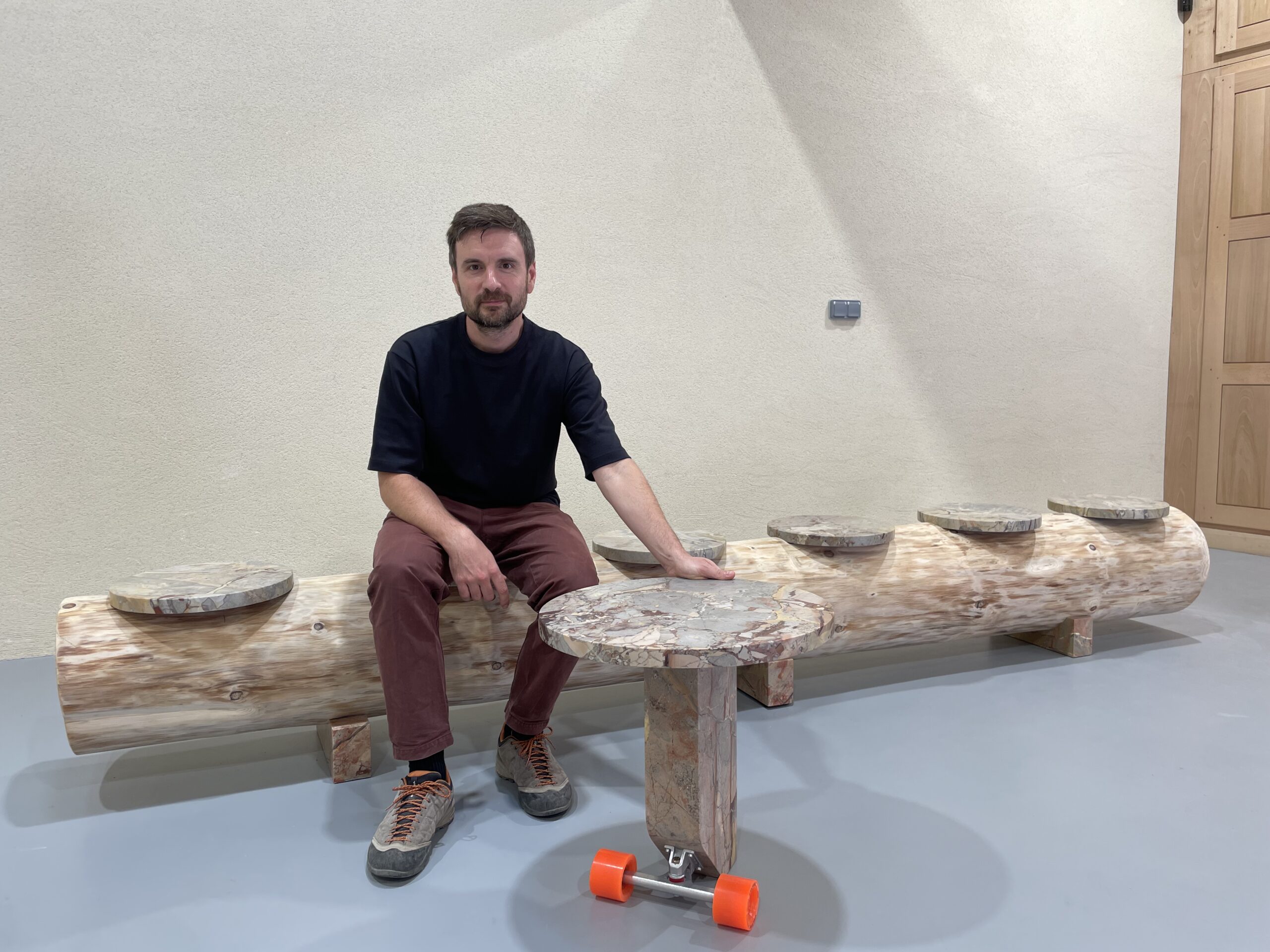Le designer Pierre Charrié assis sur son banc en marbre et bois